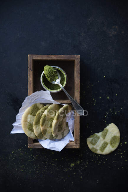 Galletas veganas de vainilla y matcha con polvo de matcha en lata con cuchara - foto de stock