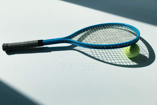 Tennis racket and ball on floor — Stock Photo