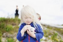 Mädchen hält Kieselsteine auf Feld — Stockfoto