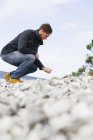 Mann pflückt Steine am Strand — Stockfoto
