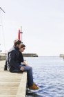 Paar sitzt auf Seebrücke — Stockfoto