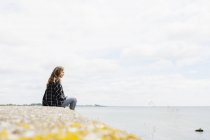 Жінка сидить на скелі на пляжі — стокове фото