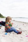 Chica sentada en la playa - foto de stock