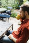 Uomo che beve caffè sul tavolo in serra — Foto stock