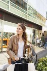 Woman with bicycle standing on street — Stock Photo