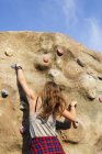 Teenage girl climbing up artificial rock — Stock Photo