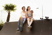Friends sitting at edge of skateboard ramp — Stock Photo