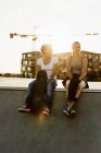 Друзі, що сидять на краю скейтборду — стокове фото