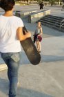 Chica mirando hembra amigo en skate park - foto de stock