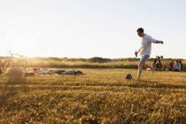 Мужчина играет в футбол на пикнике — стоковое фото