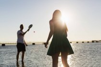 Пара, играющая в теннис на берегу — стоковое фото