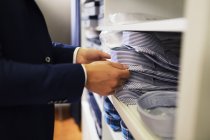 Verkäufer entfernt Hemd aus Regal — Stockfoto