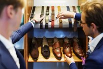 Salesman assisting customer in choosing belts — Stock Photo
