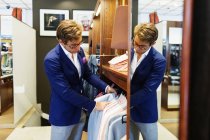 Salesman arranging suits — Stock Photo