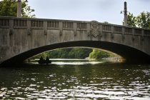 Amici pedalando barca sotto arco ponte — Foto stock