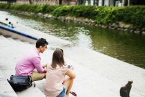 Friends sitting on steps by river — Stock Photo
