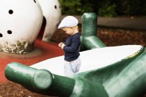 Menino de pé na estrutura no parque infantil — Fotografia de Stock