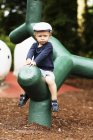 Menino sentado na estrutura verde no parque infantil — Fotografia de Stock