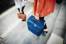 Businesswomen with luggage moving down steps — Stock Photo
