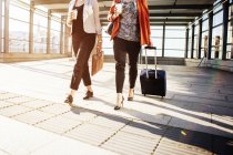 Businesswomen with luggage walking at railroad station — Stock Photo