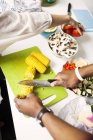 Mãos cortando legumes na cozinha — Fotografia de Stock