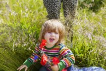 Fille tenant des fleurs sur champ herbeux — Photo de stock