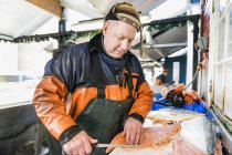Fisherman filleting salmon in fishing industry — Stock Photo