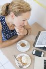 Жінка використовує технології за столом кафе — стокове фото