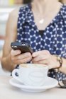 Женщина с помощью мобильного телефона с кофе — стоковое фото
