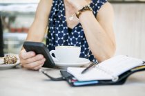 Frau benutzt Handy mit Kaffee — Stockfoto