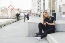 Student using mobile phone on steps — Stock Photo