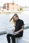 Student using laptop by river — Stock Photo