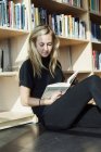 Студент читає книгу в бібліотеці коледжу — стокове фото