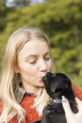 Woman kissing puppy outdoors — Stock Photo