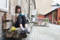 Жінка читає книгу, тримаючи чашку кави — стокове фото