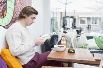 Чоловік читає книжку в кафе. — стокове фото