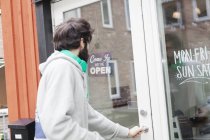 Человек, открывающий дверь кафе — стоковое фото