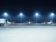 Illuminated floodlights in front of airplanes — Stock Photo