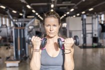 Onfident mature woman lifting dumbbells — Stock Photo