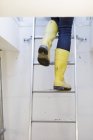 Person trägt Stiefel beim Aufstieg zur Leiter — Stockfoto