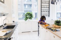 Дівчина нарізає помідори на кухні — стокове фото