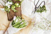Квіти на столі над білою обкладинкою столу — стокове фото
