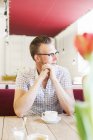 Мужчина отводит взгляд, сидя в кафе — стоковое фото