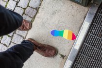 Homem andando por pegada bandeira arco-íris — Fotografia de Stock
