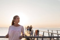 Young woman leaning on railing at pier — Stock Photo