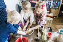 Enfants pétrissant la pâte dans un bol — Photo de stock