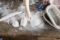 Hand dusting flour on dough — Stock Photo