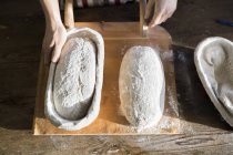 Bakers hands with dough at table — Stock Photo