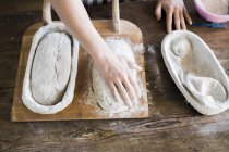 Panaderos manos con masa en la mesa - foto de stock