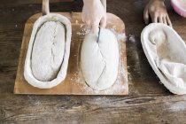 Bakers hands making design on dough — Stock Photo